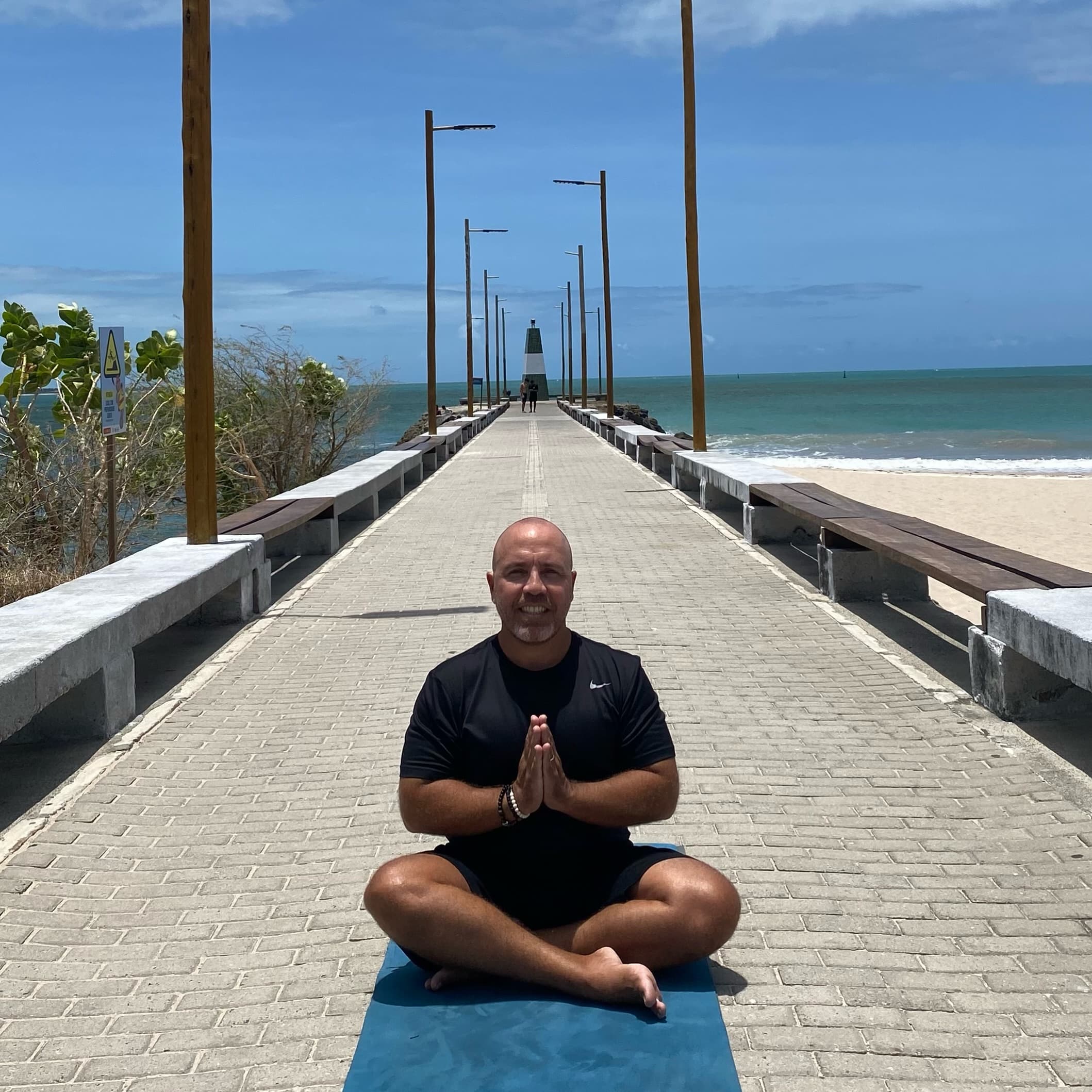 Artur França meditando em um píer à beira-mar